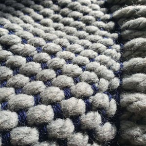 Close-up of fringe on wool blanket with twisted ends and dense knit structure.