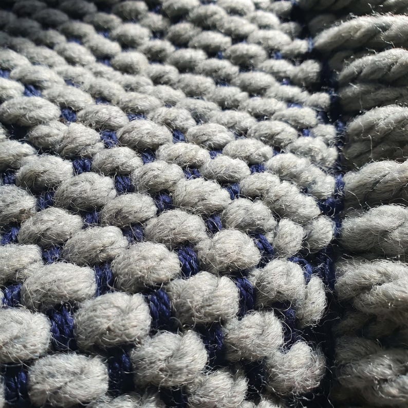 Close-up of fringe on wool blanket with twisted ends and dense knit structure.