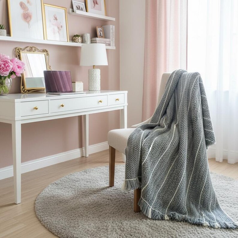 Large handmade grey crochet wool blanket with white thin accents and fringe on a sofa. 71x53 inch throw for farmhouse home decor.