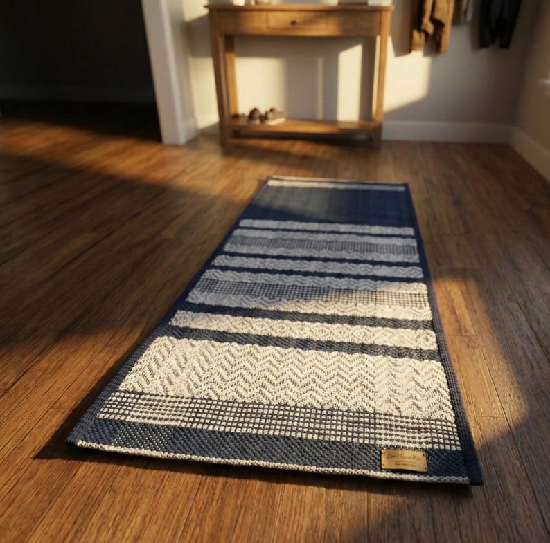 Blue and white cotton rug lying on wooden floor, simple striped design visible.