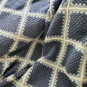 May include: A crocheted blanket with a square pattern in shades of blue and white.