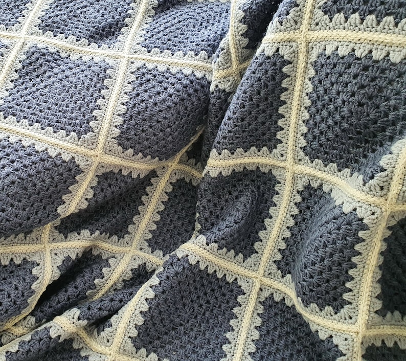 May include: A crocheted blanket with a square pattern in shades of blue and white.