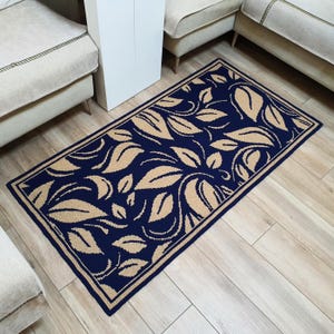 A navy blue and beige patterned rug with a floral design. The rug has a border around the edges.