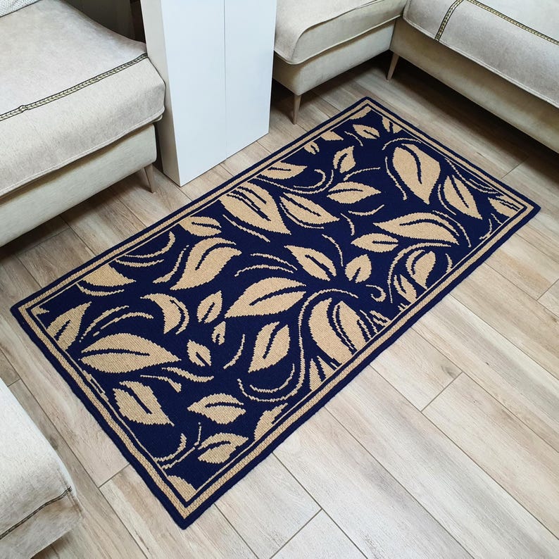 A navy blue and beige patterned rug with a floral design. The rug has a border around the edges.