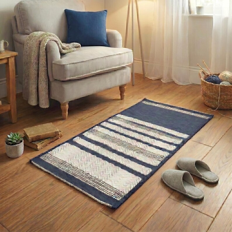 Cotton woven rug in blue and white stripes placed near an armchair in a calm interior.