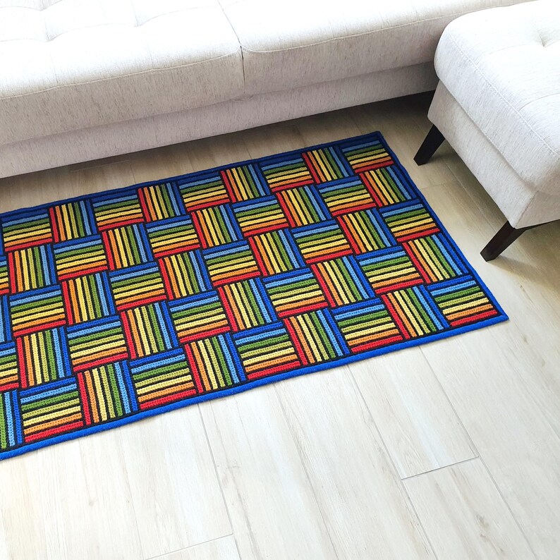 Brightly colored geometric rug placed next to a white modern bed on light wood floor.