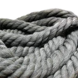A close-up of a thick, gray rope made of yarn. The chunky yarn is twisted, creating a textured and interesting texture.