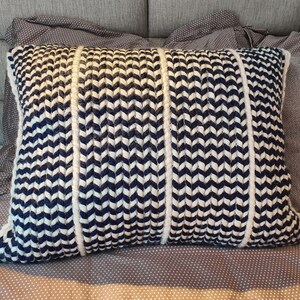 May include: A decorative throw pillow with a chevron pattern in white and navy blue. The pillow is made of a soft, woven fabric.