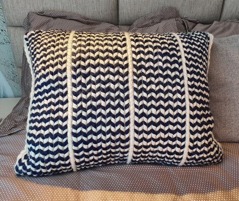 May include: A decorative throw pillow with a chevron pattern in white and navy blue. The pillow is made of a soft, woven fabric.