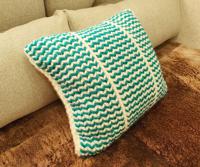 May include: A teal and white patterned throw pillow with a chevron design. The pillow is made of a soft, woven fabric.