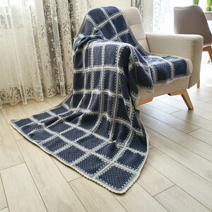 May include: A blue and white crocheted throw blanket with a square pattern. The blanket is draped over a chair.