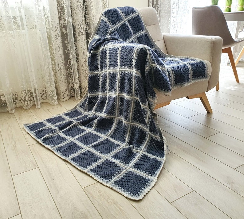 May include: A blue and white crocheted throw blanket with a square pattern. The blanket is draped over a chair.