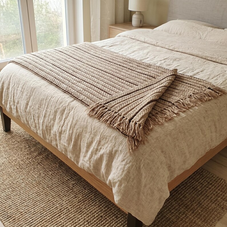 Neutral wool blanket folded on a bed, showing soft texture and structured knit pattern.
