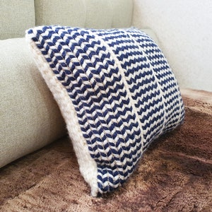 May include: A blue and white striped throw pillow with a chevron pattern. The pillow is made of a woven fabric and has a soft, comfortable texture.