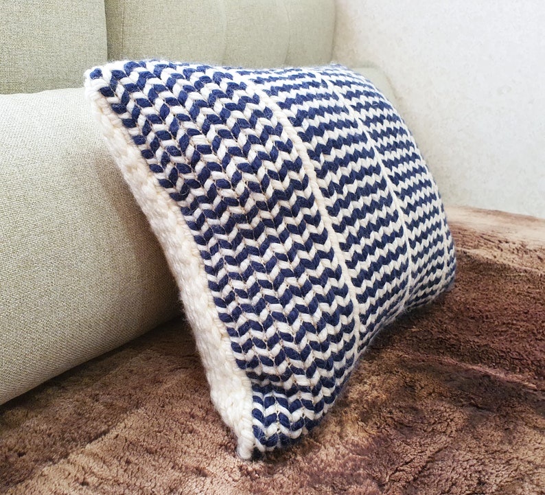 May include: A blue and white striped throw pillow with a chevron pattern. The pillow is made of a woven fabric and has a soft, comfortable texture.