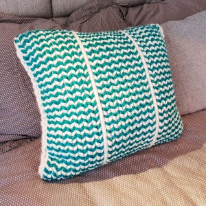 May include: A teal and white chevron patterned throw pillow with three white stripes down the center.