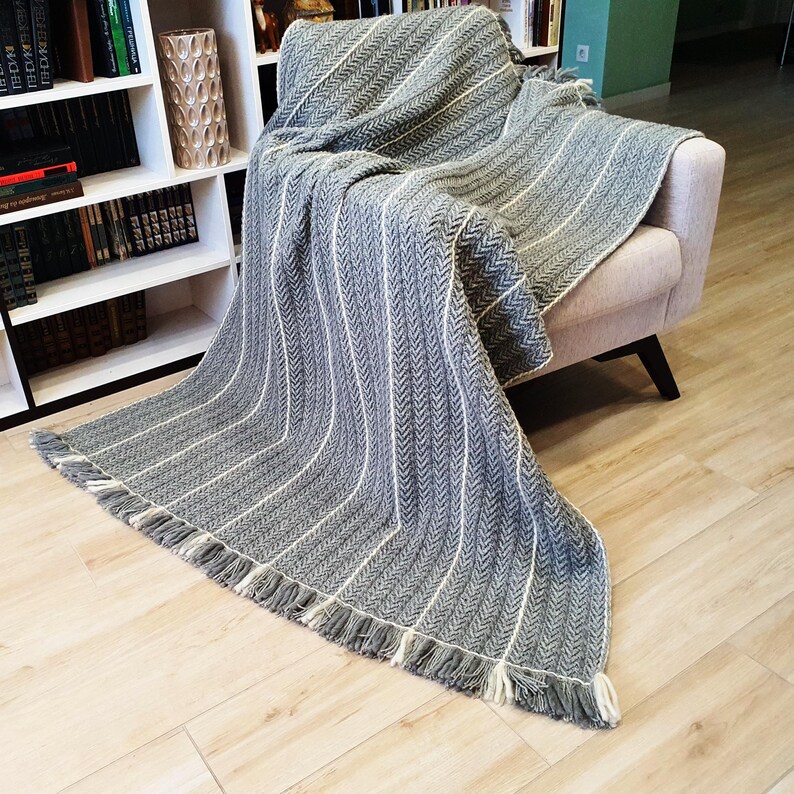 A gray and white striped throw blanket with fringe on the edges. The blanket is draped over a chair.