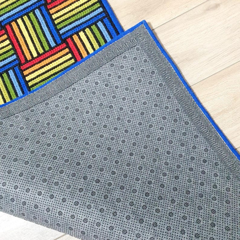 A vibrant handmade wool carpet featuring rows of alternating vertical and horizontal stripes.