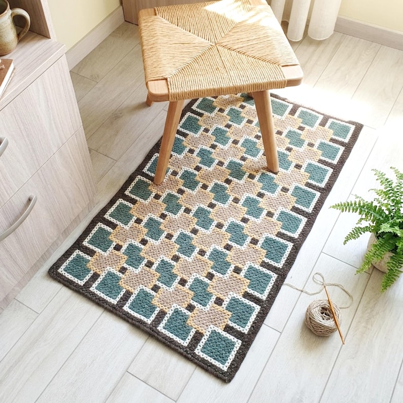 Small wool rug in Beige, Brown, Green and Teal placed near a chair, structured geometric pattern, compact accent piece