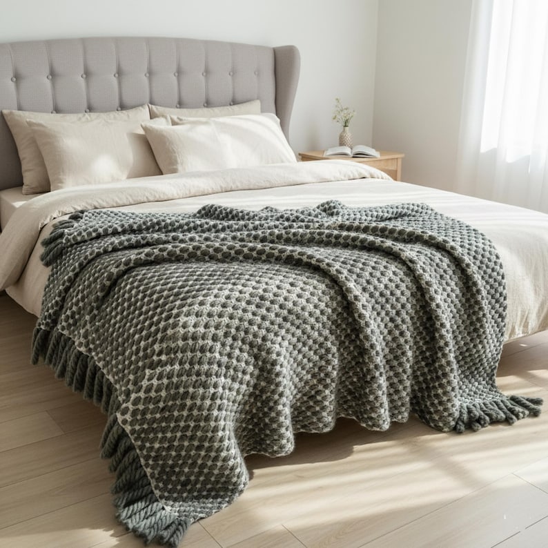 Full view of handmade gray wool blanket with textured crochet pattern on a neutral interior background