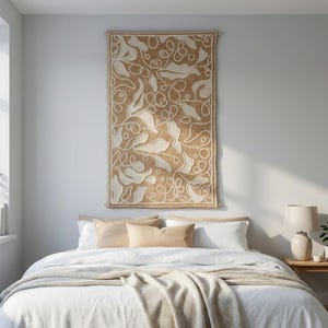 Wool embroidery wall panel with organic leaf shapes and raised texture in neutral tones in a bedroom.