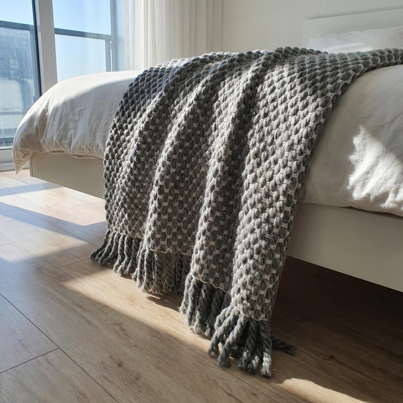 Textured wool blanket with visible crochet structure and thick yarn resting on a bed