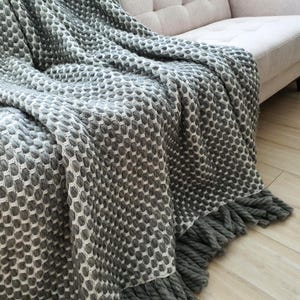 Large gray crochet wool blanket folded with emphasis on texture and volume