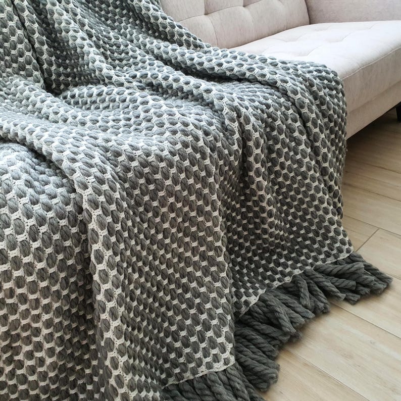 Large gray crochet wool blanket folded with emphasis on texture and volume