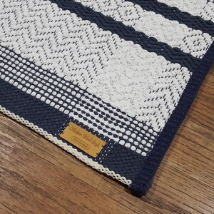 Detailed view of blue and white cotton rug showing stitch variation and density.