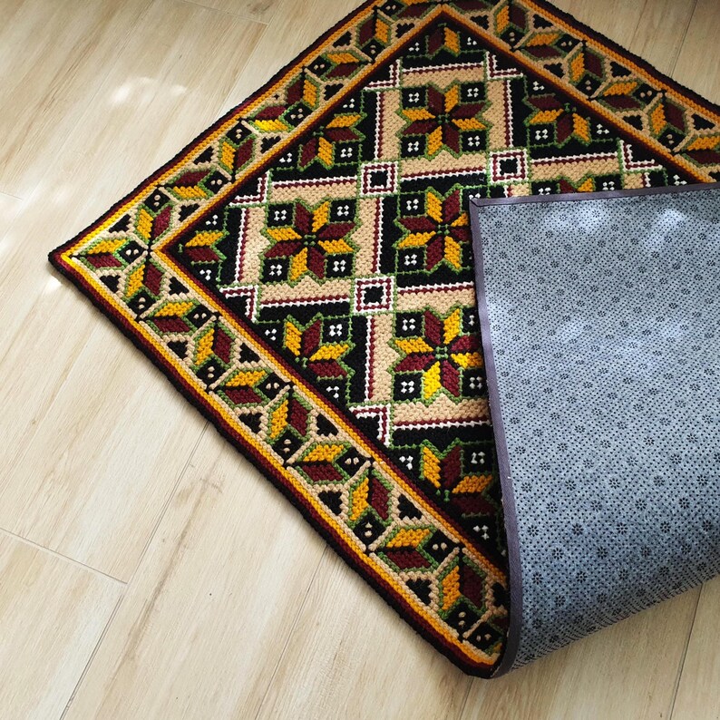 Close-up wool rug backing. A handmade embroidery runner with Ukrainian patter has an anti-slip lining on the floor.