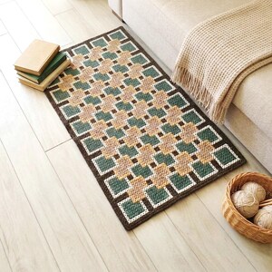 Wool accent rug in Beige, Brown, Green and Teal colors positioned next to a sofa, geometric design defining the space