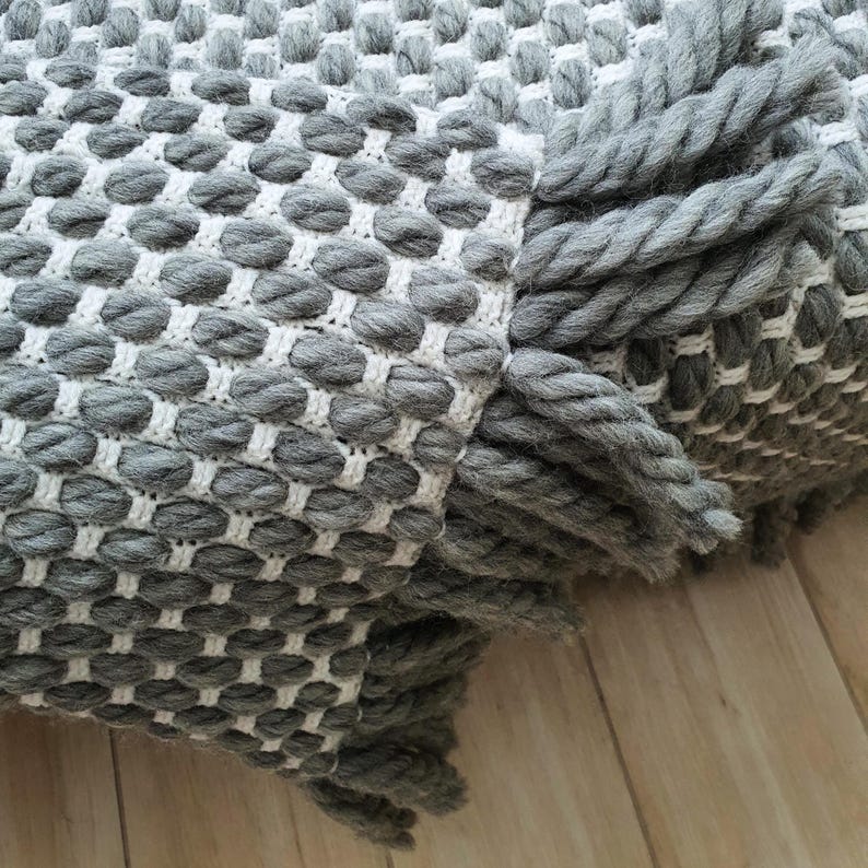 Chunky crochet blanket made of thick wool yarn with visible structure and natural imperfections