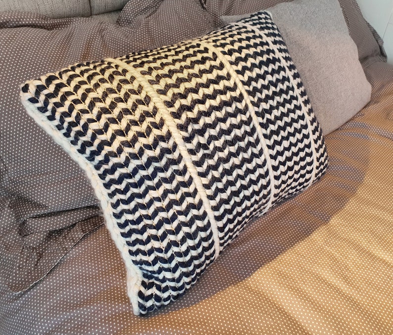 May include: A black and white patterned throw pillow with a chevron design. The pillow is made of a soft, textured fabric and is perfect for adding a touch of style to any room.