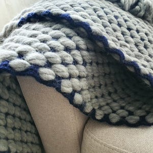Edge detail of chunky knit blanket showing thick yarn loops and finishing.