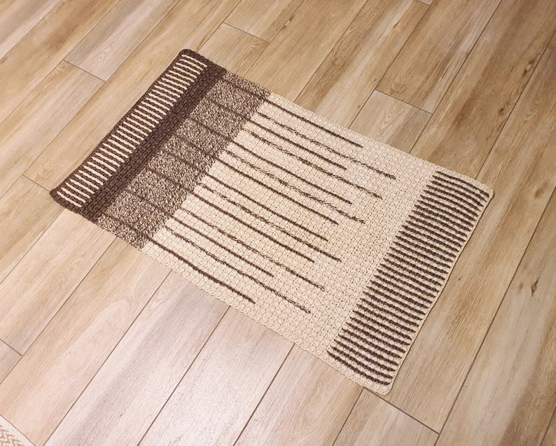 May include: A rectangular brown and cream rug with a striped pattern. The rug has a textured surface and is made of woven fibers.