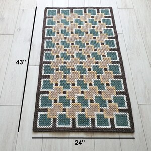 Full view of handmade wool rug in Beige, Brown, Green and Teal, geometric pattern, rectangular shape on light floor