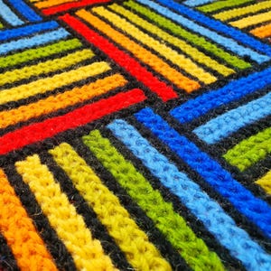 Close-up of wool embroidery showing intricate hand-stitched details in green, blue, and red.