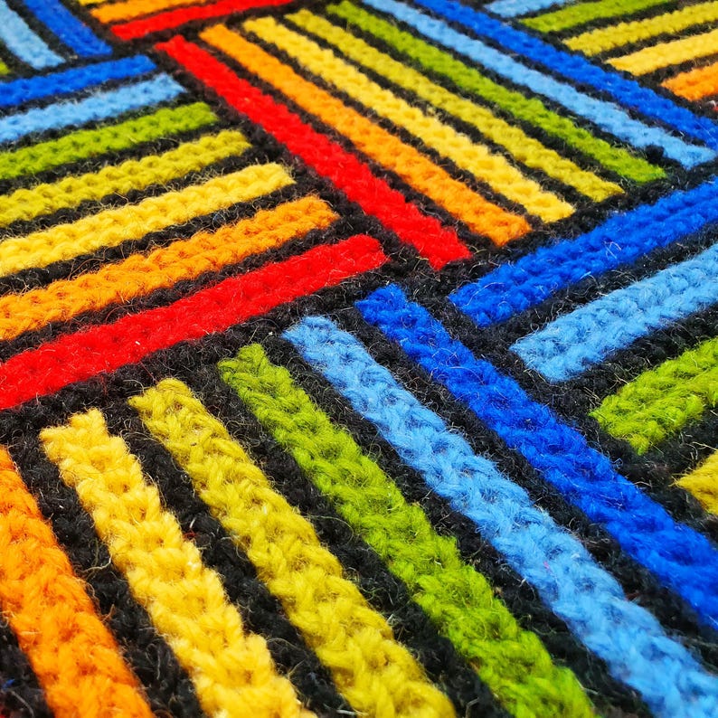Close-up of wool embroidery showing intricate hand-stitched details in green, blue, and red.