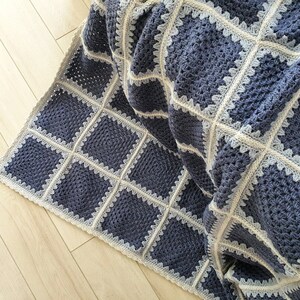 May include: A crocheted throw blanket with a square pattern in shades of blue and white.