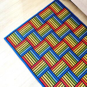 Side view of the rug showing the blue border and raised stitch texture.