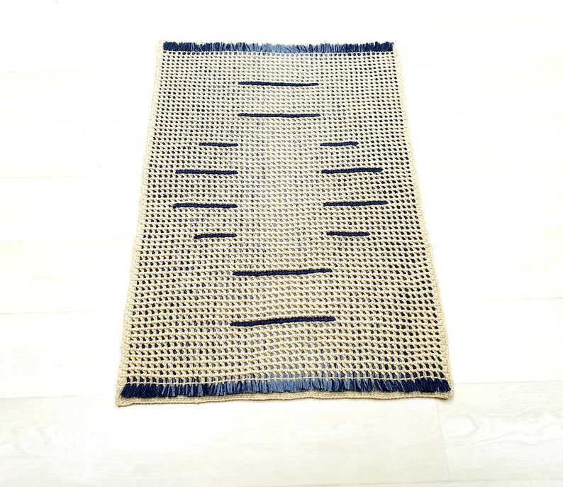 May include: A beige woven rug with a fringe border and dark blue stripes.