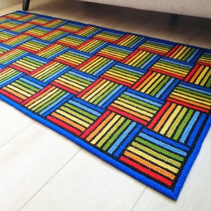 Hand-stitched textile art floor mat with saturated yellow, orange, and blue hues.