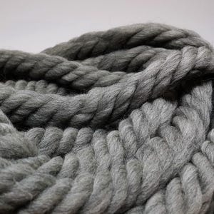Close-up of a thick, gray yarn with a chunky, rope-like texture. The yarn is soft and it is perfect for knitting or crocheting.