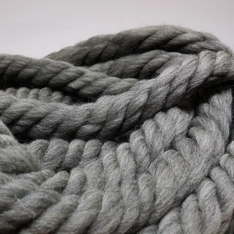 Close-up of a thick, gray yarn with a chunky, rope-like texture. The yarn is soft and it is perfect for knitting or crocheting.
