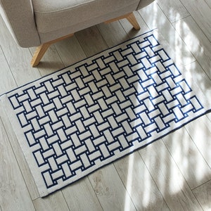 May include: A white and blue woven rug with a geometric pattern. The rug has a rectangular shape and is made of a soft, durable material.