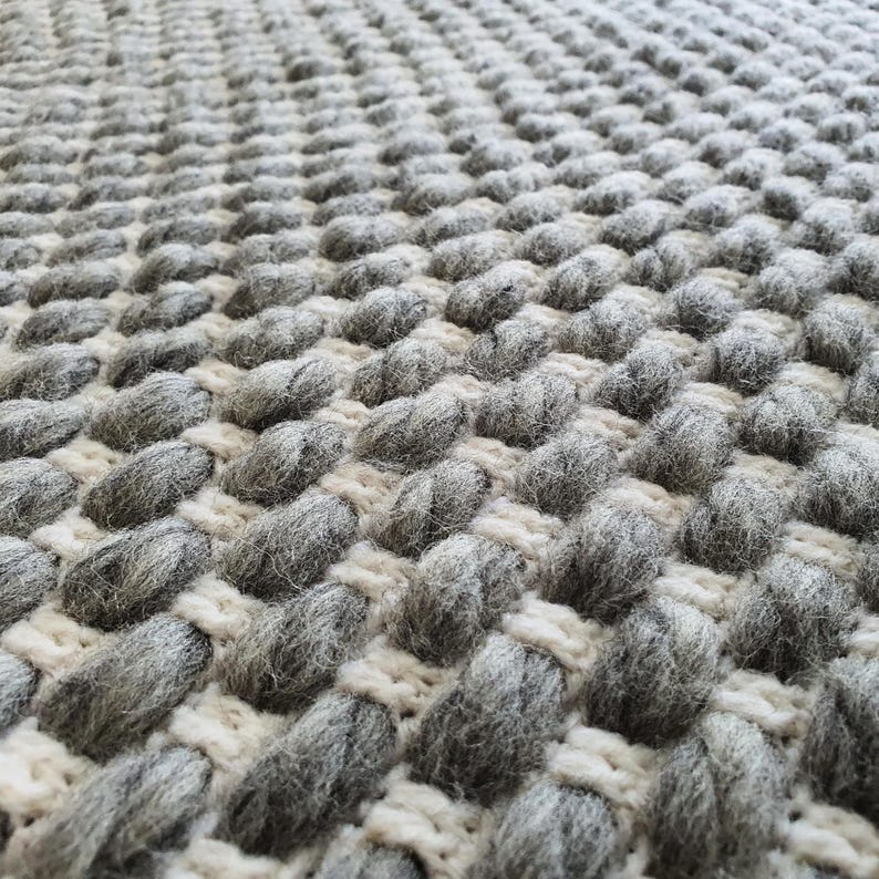 Chunky crochet blanket made of thick wool yarn with visible structure and natural imperfections