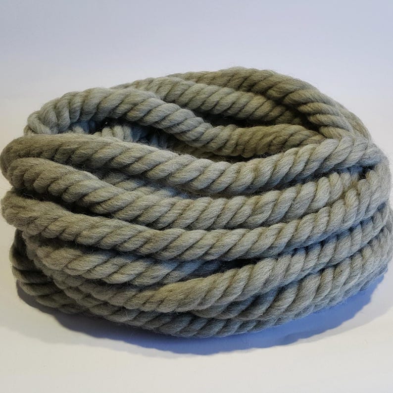 A close-up of a thick, gray wool yarn into a circular shape. The chunky yarn is made of a soft, natural material and has a textured surface.