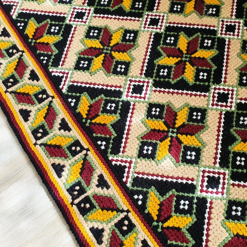 Close-up detail of thick wool embroidery on natural jute backing. Artisan hand-stitched texture suitable as a woven wall tapestry or cozy bedside rug.