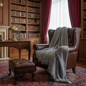 Large handmade grey crochet wool blanket with white thin accents and fringe on a sofa. 71x53 inch throw for farmhouse home decor.