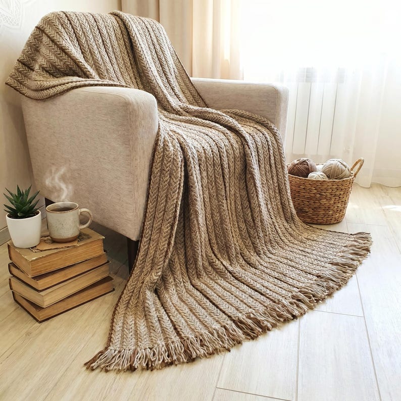 Handmade wool throw in beige color draped over an armchair, showing textured crochet pattern.